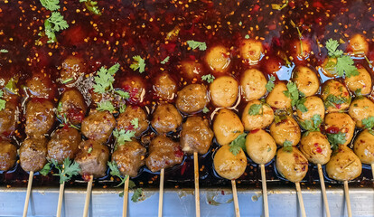 Beef meatballs, chicken meatballs, and pork meatballs grilled and soaked in spicy dipping sauce for...