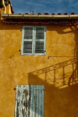 Window with shatters on the yellow wall