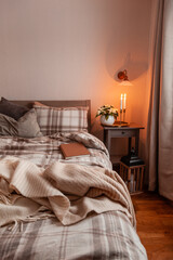 Fototapeta na wymiar cozy scandinavian bedroom interior in natural tones, blanket candles houseplants