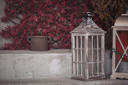 Vintage lanterne and pot in front of red ivy wooden wall. decorative wooden lantern in autumn garden. Garden decoration in rustic style. Exterior element, home decor.