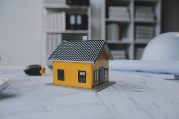 architectural model of houses on desk with drawing technical tools and blueprint rolls, isolated on...