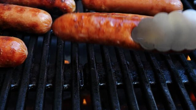 Grilled sausages Bockwurst on barbecue grill grate. Turn sausages over. Close up