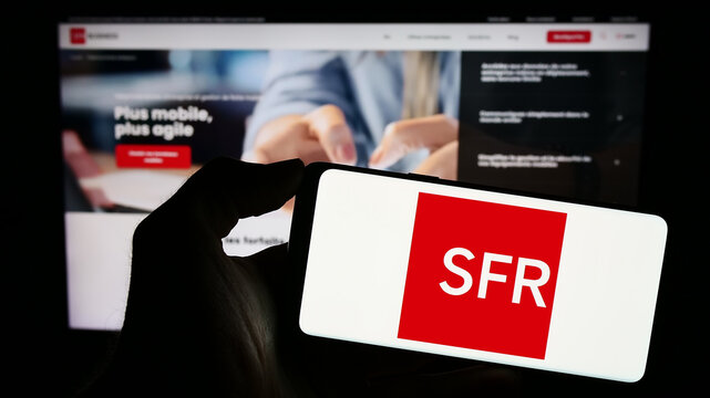 Stuttgart, Germany - 12-07-2023: Person holding mobile phone with logo of French company Soci&eacute;t&eacute; Fran&ccedil;aise du Radiot&eacute;l&eacute;phone (SFR) in front of web page. Focus on phone display.