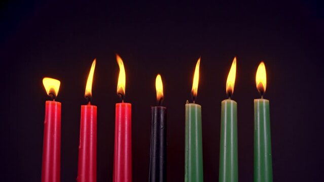 Kwanzaa festival concept with seven candles red, black and green over black background, copy space