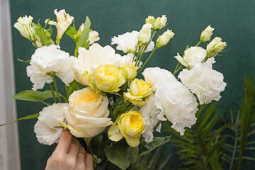 Floristry. Flowers. A florist girl collects a bouquet of white and yellow roses. Blurred background.