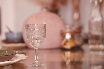 Glass in the foreground in Christmas minimalistic pastel table ware in the interior