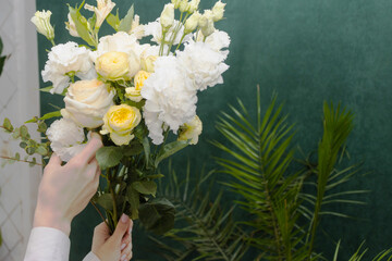 Floristry. Flowers. A florist girl collects a bouquet of white and yellow roses. Blurred background.