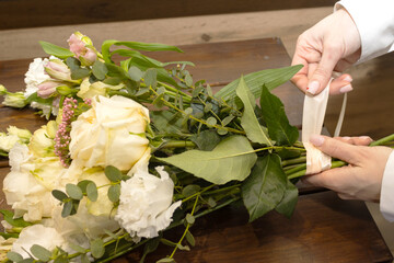 Floristry. Flowers. A florist girl collects a bouquet on the desktop, brown in color.