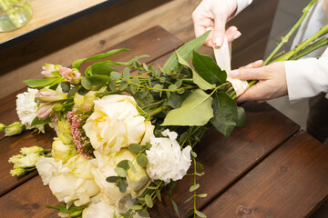 Floristry. Flowers. A florist girl collects a bouquet on the desktop, brown in color.