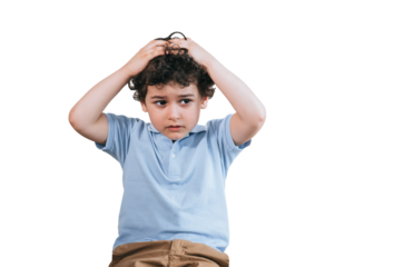 Unhappy little curly boy feels bad putting hands on head with desperate face expression against transparent background with copy space for ad. Failure concept. Kid with headache.