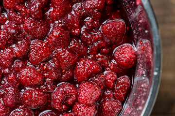 Fresh red raspberry berry, covered with granulated sugar for jam preparation in bowl, top view, closeup. Background and texture of raspberries with sugar - obrazy, fototapety, plakaty