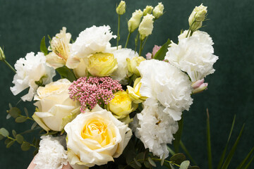 Floristry. Flowers. A florist girl collects a bouquet of white and yellow roses. Blurred background.