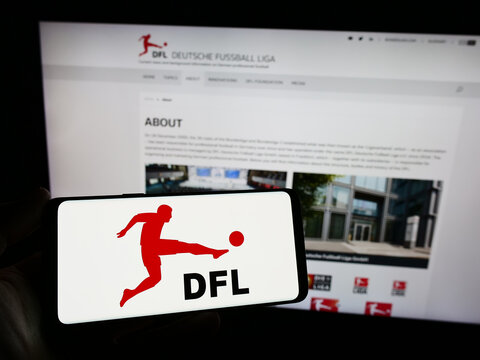 Stuttgart, Germany - 12-07-2023: Person holding smartphone with logo of German football company DFL Deutsche Fu&szlig;ball Liga GmbH in front of website. Focus on phone display.