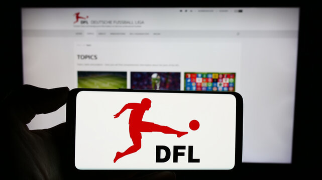 Stuttgart, Germany - 12-07-2023: Person holding cellphone with logo of German football company DFL Deutsche Fu&szlig;ball Liga GmbH in front of webpage. Focus on phone display.