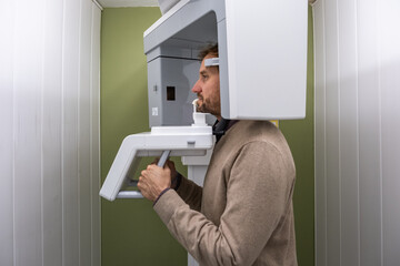 A patient at the x-ray machine taking a panoramic x-ray of his mouth.
