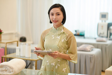 Portrait of smiling spa salon manager with tablet computer waiting for client