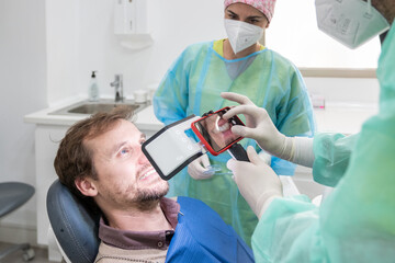 A dentist and his assistant taking pictures of a patient's mouth with a special light.
