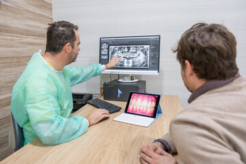 A dentist explaining a diagnosis to a patient in his office at the clinic.