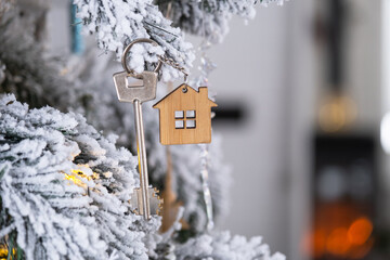 Key to the house with a keychain is hanging on the Christmas tree. A gift for New Year, Christmas....