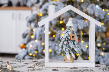 Key on Christmas tree and tiny house on cozy home with Christmas decor on table of festive white...