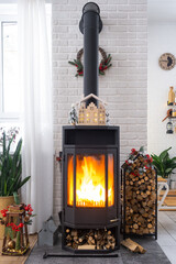 Metall black stove, burning hearth fireplace in white Festive interior of house is decorated for...