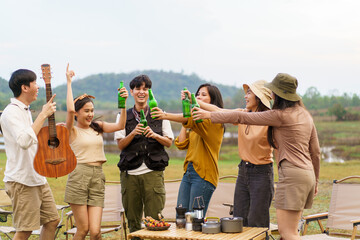 Asian young women and men celebrating with a bottle of a beer together.