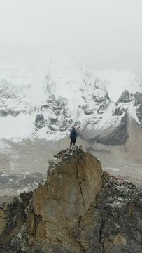 Hiker Man on Top of Kalapatthar Mountain Looking on Khumbu Icefall, Everest and Nuptse. Himalaya, Nepal. Aerial View. Drone is Orbiting. Vertical Video
