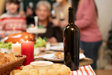 Wine bottle on dinner table and family background in christmas time at home