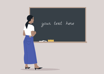 A young woman seen from behind writing on a classroom chalkboard