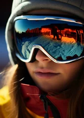 Poster Portrait of young woman at the ski resort on the background of mountains and blue sky.A mountain range reflected in the ski mask © Jasper W