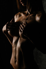 athletic figure without underwear of a sexy girl belly with drops of sweat and water in the gym in a low key	