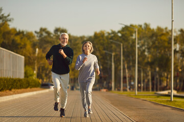 Happy retired couple jogging together. Healthy smiling senior husband and wife in sportswear...