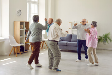 Full length portrait of a group of happy smiling senior people men and women having fun and dancing enjoying activities in retirement home together. Leisure time in nursing home concept.