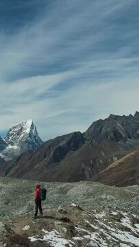 Ama Dablam Mountain, Lhotse South Face and Hiker Man on Sunny Day. Blue Sky. Himalaya, Nepal. Aerial View. Drone is Orbiting. Vertical Video