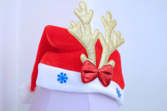 Christmas hat decorated by golden deer antler and red ribbon