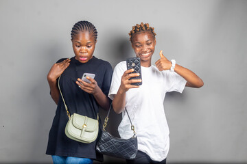 two beautiful young black women viewing content together on a phone feeling excited
