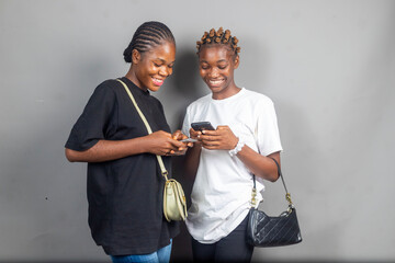 beautiful young african women feeling excited and happy while looking at their mobile phones