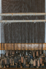 Ancient weaving loom ith warp yarns hang freely from a bar with loom weights, viking age