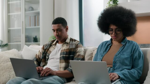 African American gadget addict couple internet addicted husband and wife social media virtual game addiction man and woman working using two laptops play with computers at home relationship problem