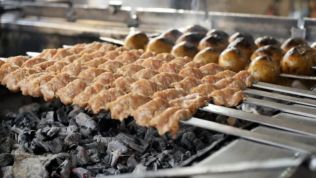 Place many raw lula kebabs on metal skewers on a grill with hot wood coals to bake a meat kebab consisting of minced meat. National Middle Eastern and Western Asian food