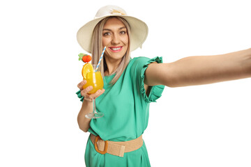 Beautiful young woman in a green dress holding a cocktail and taking a selfie