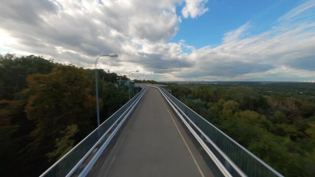 FPV drone flying along the road, Aerial view of road and city, Kiev, Ukraine, Park Bridge Mariinsky Park Kiev Ukraine Landmark, Green grass hill in foreground. Sidewalk neatly laid over the hill