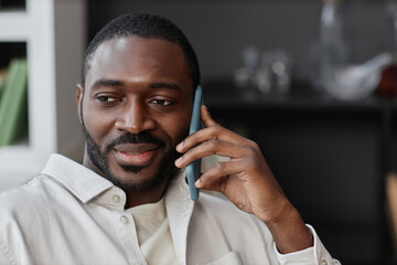 Close up portrait of adult African American man speaking by phone at home with smile, copy space