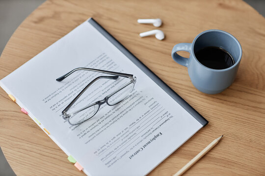 Top view background image of employment contract with eyeglasses on wooden table in office, copy space