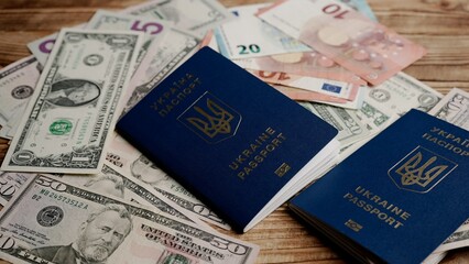 Close up shot of person identity document. Money usa dollars, euro bills scattered on the table and two ukrainian passports laying over.