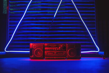 Stereo tape recorder on the floor in neon lights background.