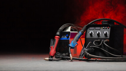 Welding concept background. Semi automatic welding machine and plasma cutter close up on the floor...