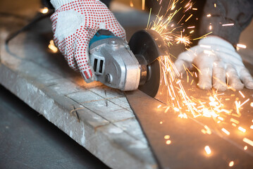 Man is cutting a metal sheet by angle grinder saw.