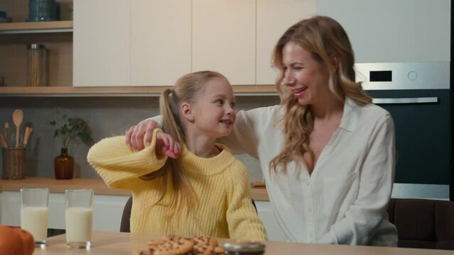 Mother And Little Daughter Cuddle At Kitchen Table Breakfast Laughing Smiling Talking Hold Hands Dancing To Music Moving Dance Mom With Child Girl Hugging Embracing Kid Family Love Bonding Cuddling