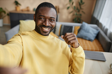 Portrait of smiling adult Black man looking at camera taking selfie photo or recording video at...